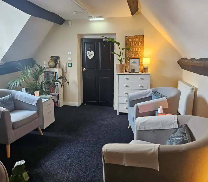 Cosy therapy room with sofas and bookshelf.